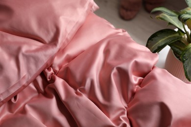 Photo of Closeup view of bed with beautiful pink silk linens indoors