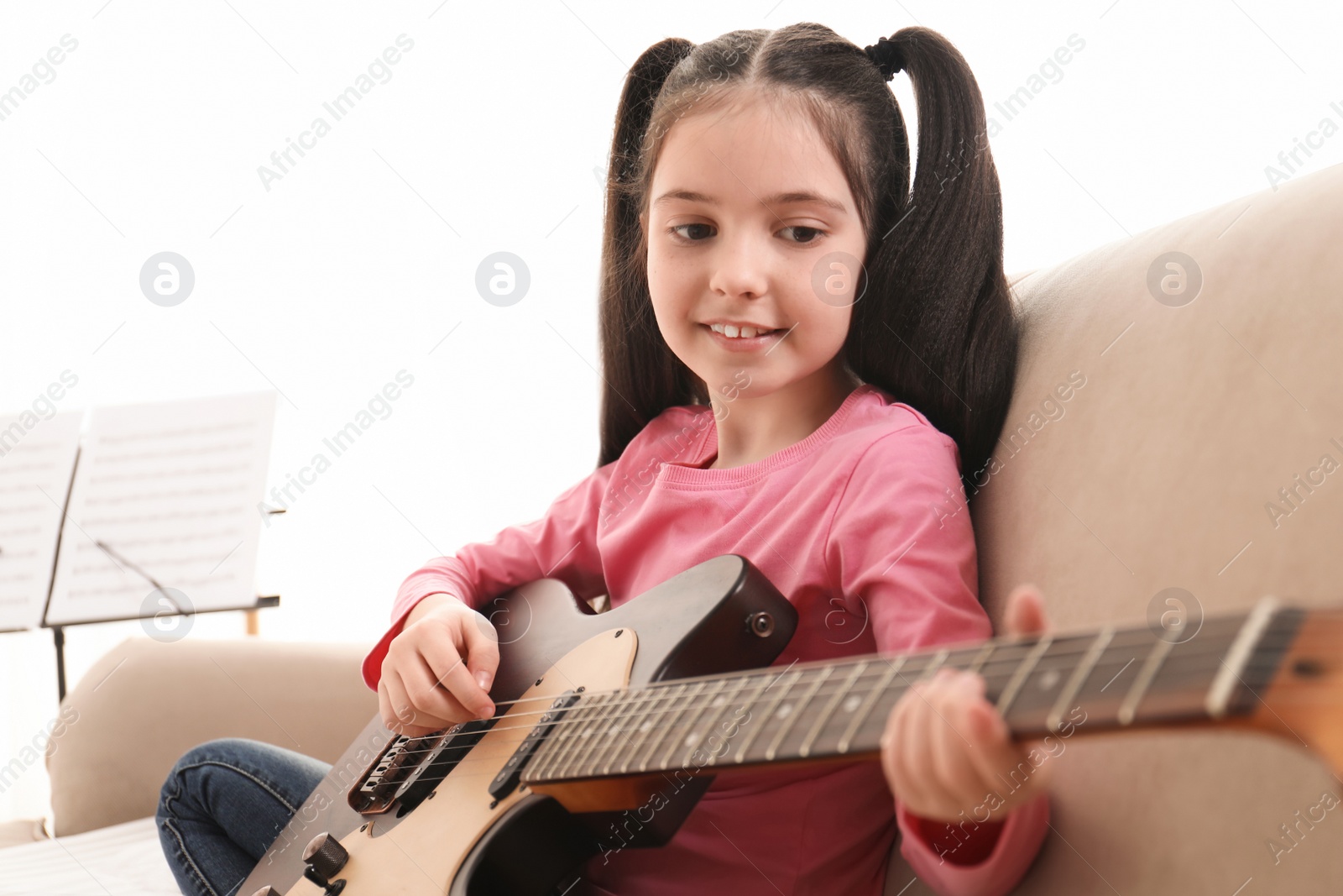 Photo of Little girl playing guitar at home. Learning music notes