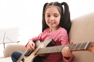 Photo of Little girl playing guitar at home. Learning music notes