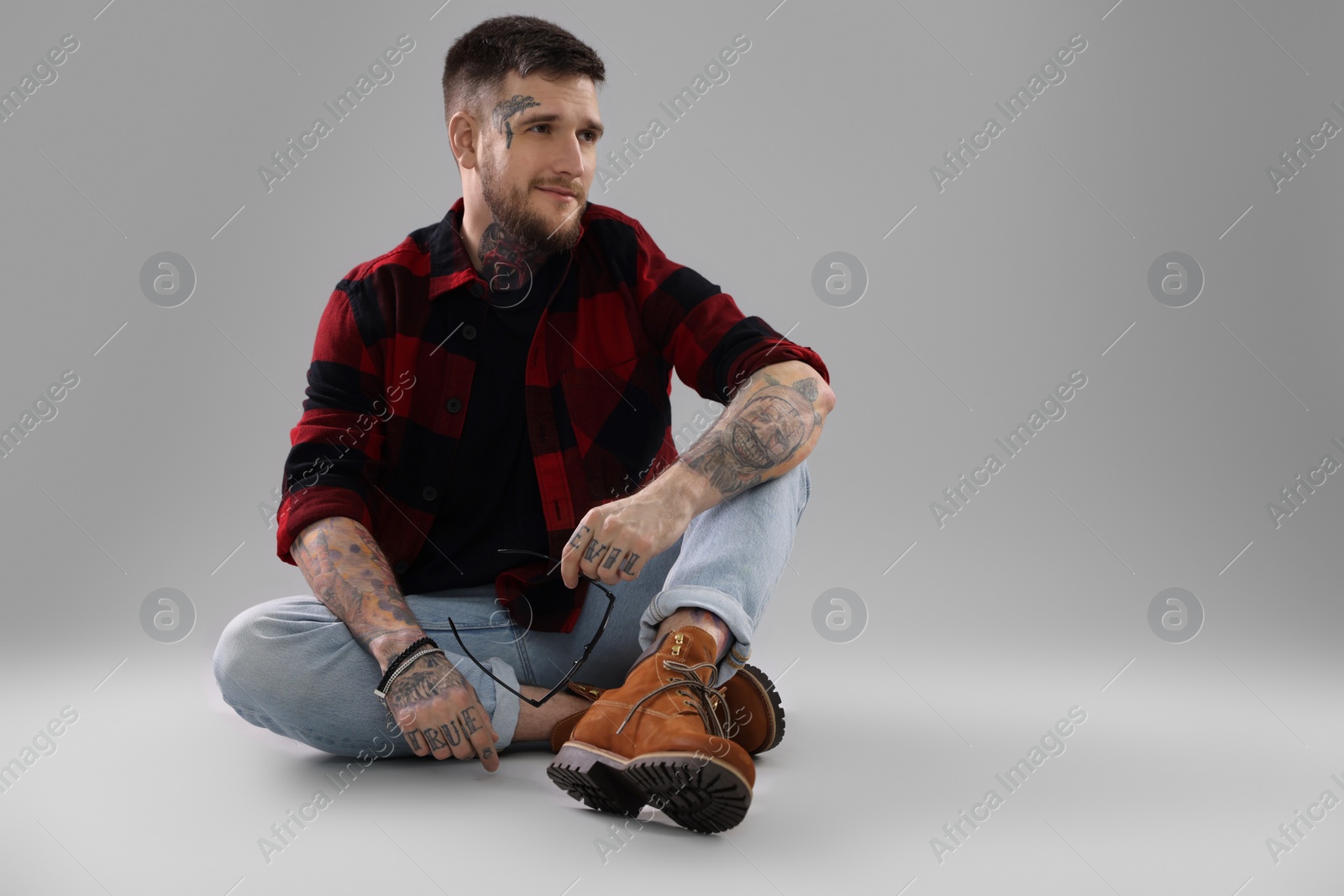 Photo of Handsome hipster man sitting on light grey background