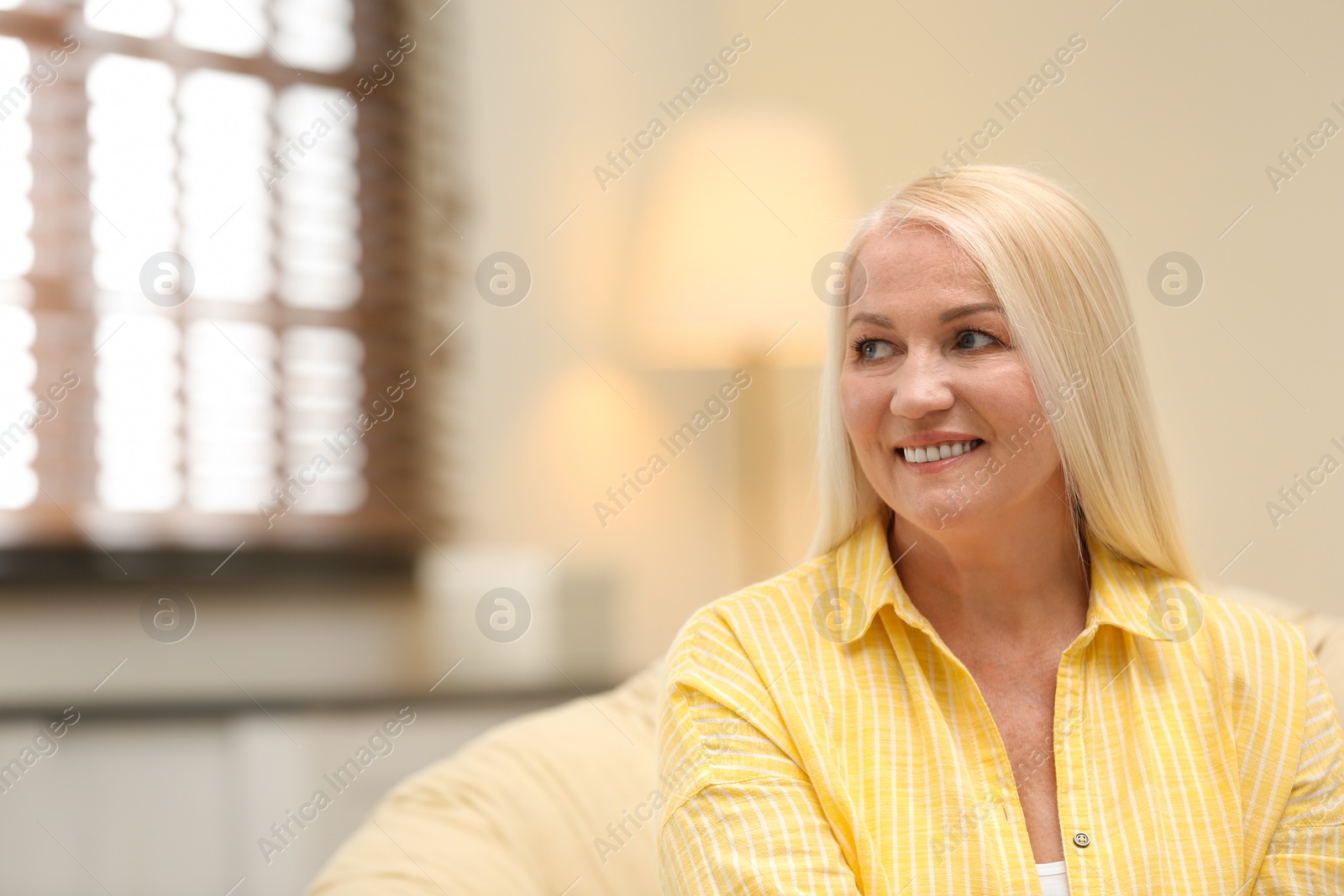 Photo of Portrait of happy mature woman sitting in papasan chair at home