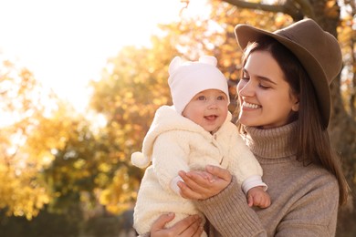 Photo of Happy mother with her baby daughter in park on sunny autumn day, space for text
