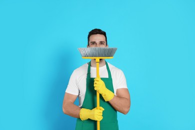 Man with yellow broom on light blue background