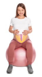 Photo of Sporty pregnant woman with kinesio tapes doing exercises on fitball against white background