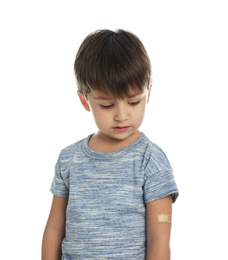 Little boy with sticking plaster on arm against white background