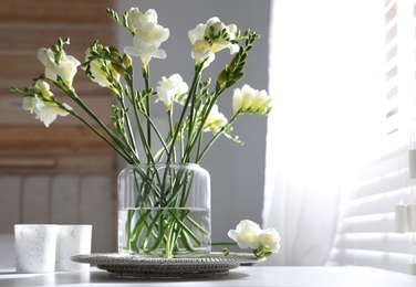 Photo of Beautiful spring freesia flowers on table in room