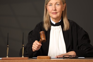 Judge striking mallet at wooden table indoors, selective focus