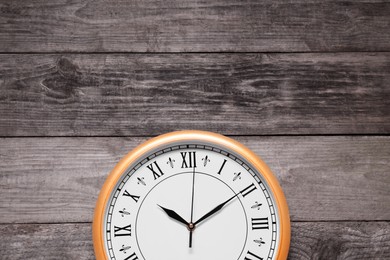 Photo of Stylish round clock on wooden table, top view with space for text. Interior element