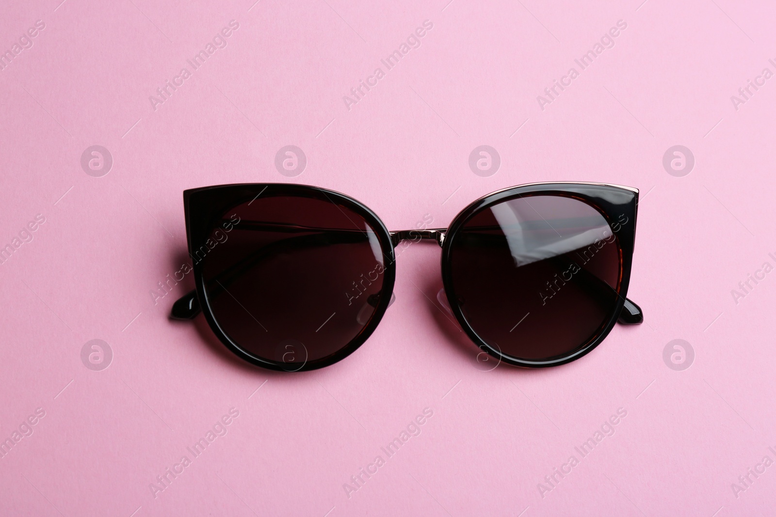 Photo of Stylish sunglasses on pink background, top view. Fashionable accessory