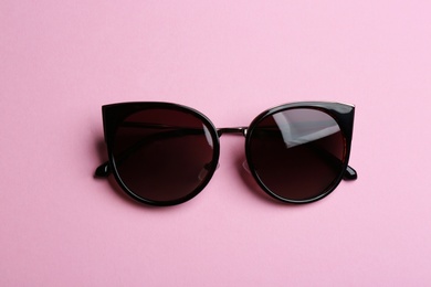 Photo of Stylish sunglasses on pink background, top view. Fashionable accessory