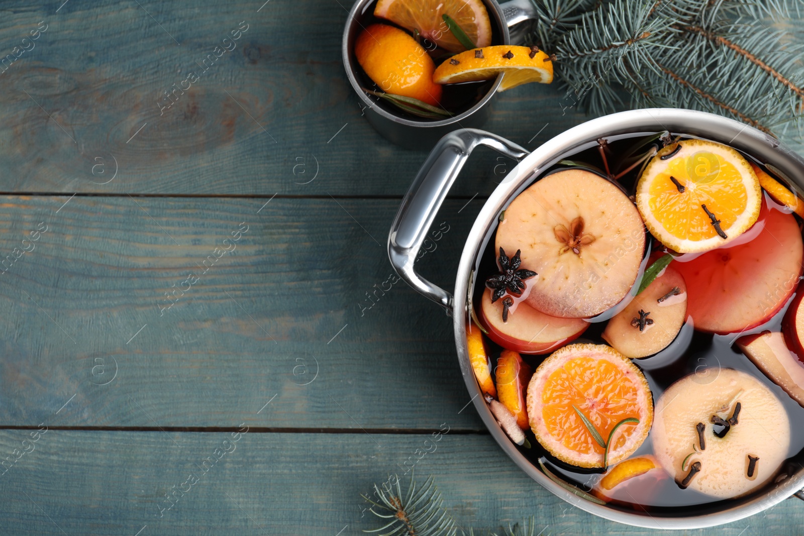 Photo of Tasty mulled wine with spices on blue wooden table, flat lay. Space for text