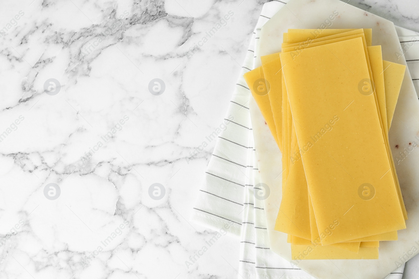 Photo of Uncooked lasagna sheets on white marble table, top view. Space for text