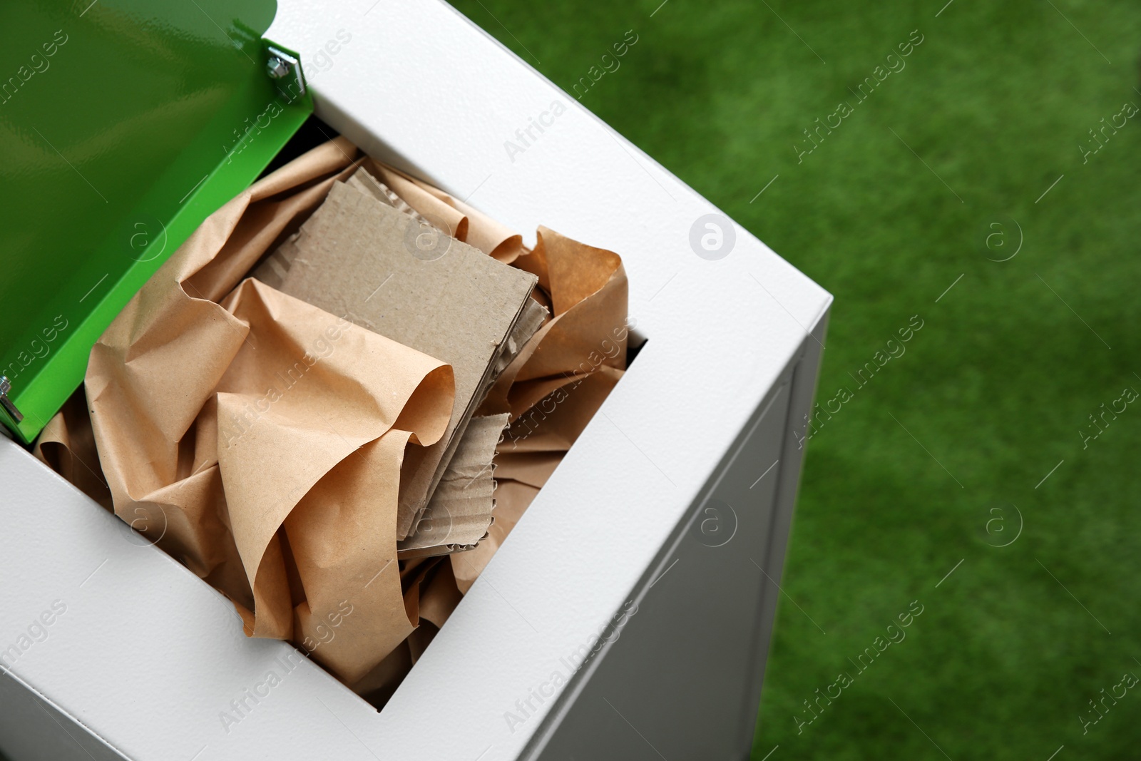 Photo of Trash bin with paper and cardboard on color background, space for text. Recycling concept