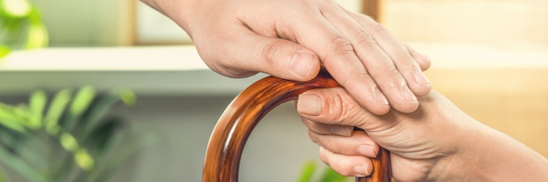 Image of Caregiver and elderly woman with walking cane at home, closeup. Banner design