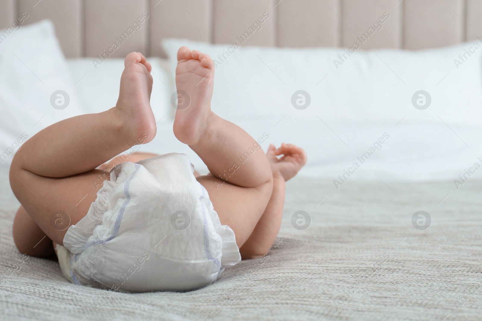 Photo of Cute little baby in diaper on bed at home. Space for text