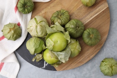 Photo of Fresh green tomatillos with husk on gray table, flat lay