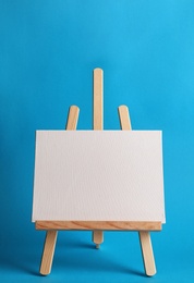 Photo of Wooden easel with blank canvas board on color background. Children's painting