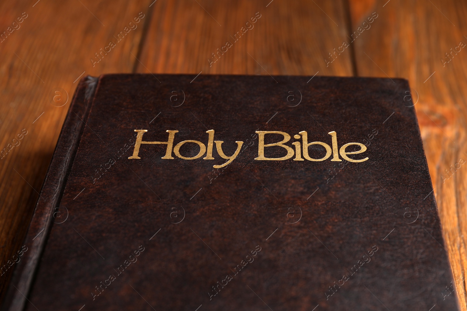 Photo of Hardcover holy Bible on wooden table, closeup