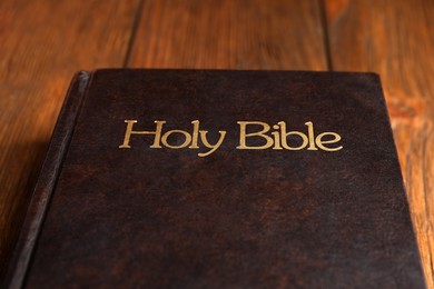 Photo of Hardcover holy Bible on wooden table, closeup