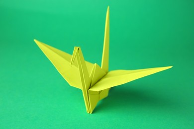 Photo of Paper origami crane on green background, closeup