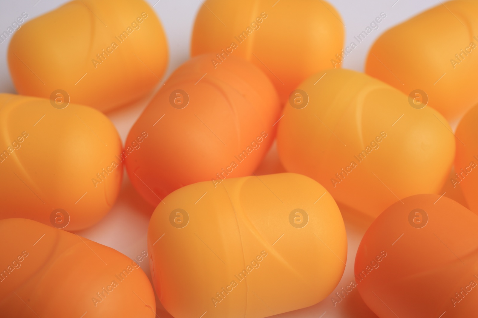 Photo of Sveti Vlas, Bulgaria - June 30, 2023: Orange plastic capsules from Kinder Surprise Eggs on white background, closeup