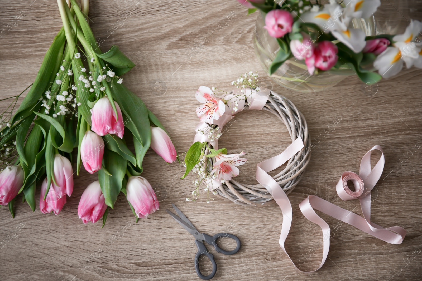 Photo of Decorator's workplace with unfinished wreath and beautiful flowers, top view