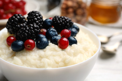 Photo of Delicious rice pudding with berries, closeup view