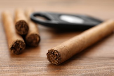 Photo of Many expensive cigars on wooden table, closeup