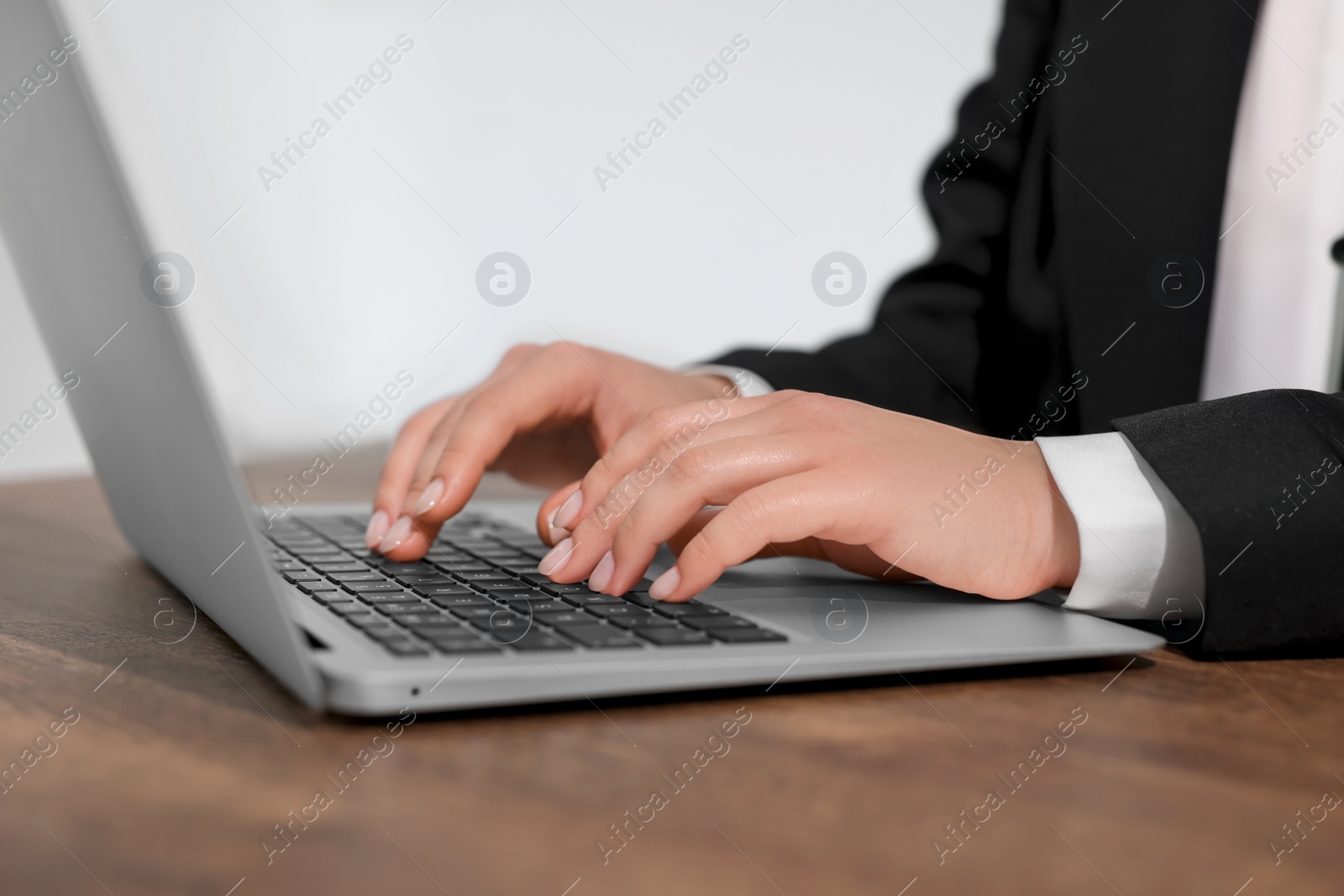 Photo of Woman working on laptop at wooden table closeup. Electronic document management