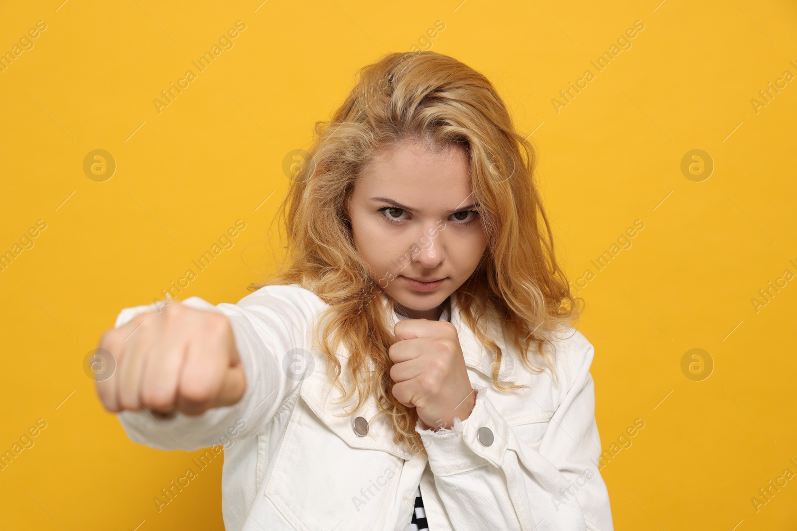 Photo of Young woman ready to fight on yellow background