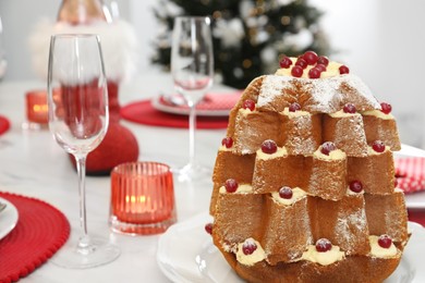 Photo of Delicious Pandoro Christmas tree cake decorated with powdered sugar and berries on white marble table