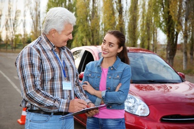 Senior instructor with clipboard and woman outdoors. Get driving license