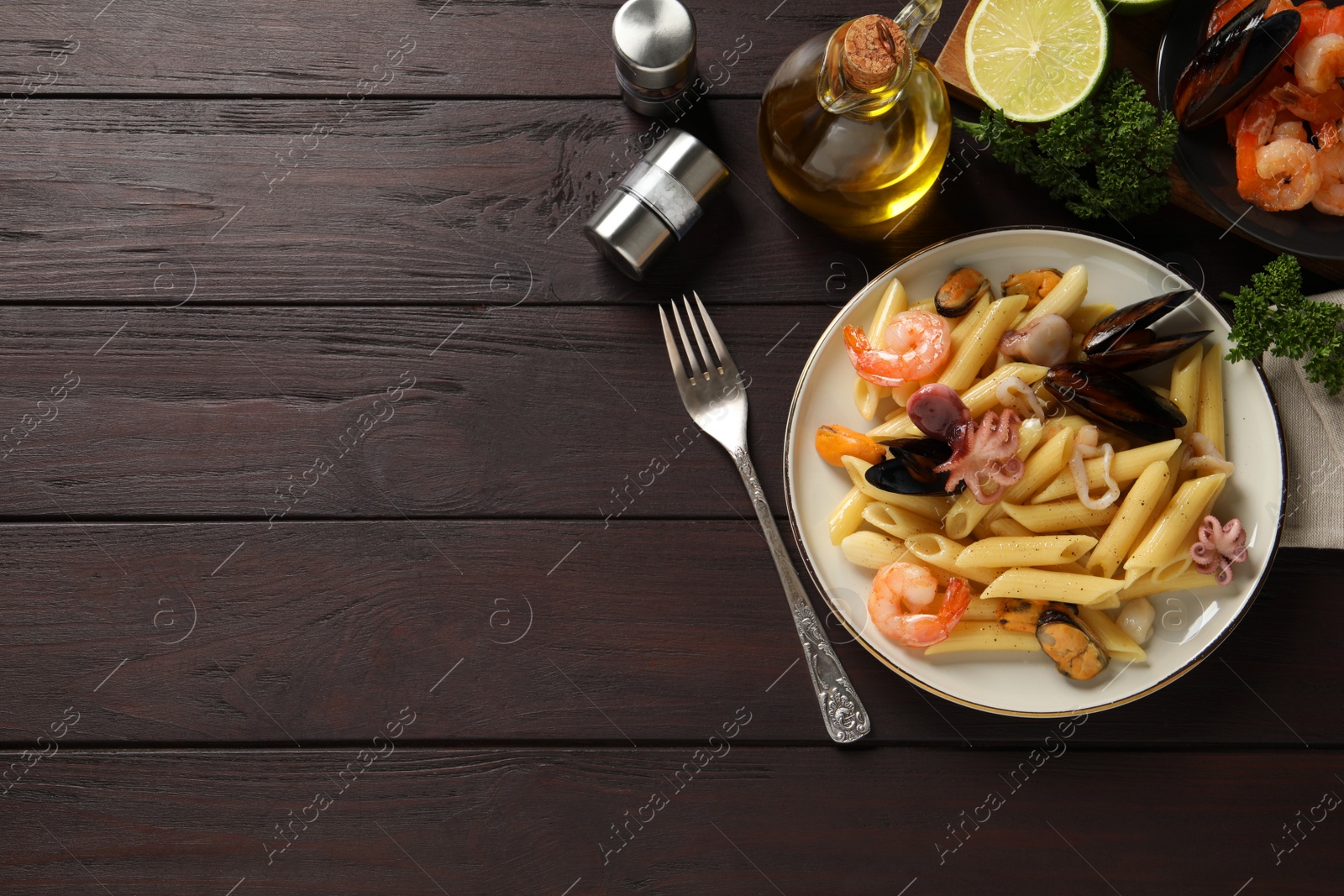 Photo of Delicious pasta with seafood served on wooden table, flat lay. Space for text