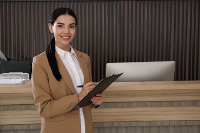 Photo of Receptionist with clipboard near countertop in office, space for text