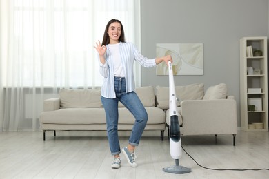 Photo of Happy woman with steam mop showing ok gesture at home