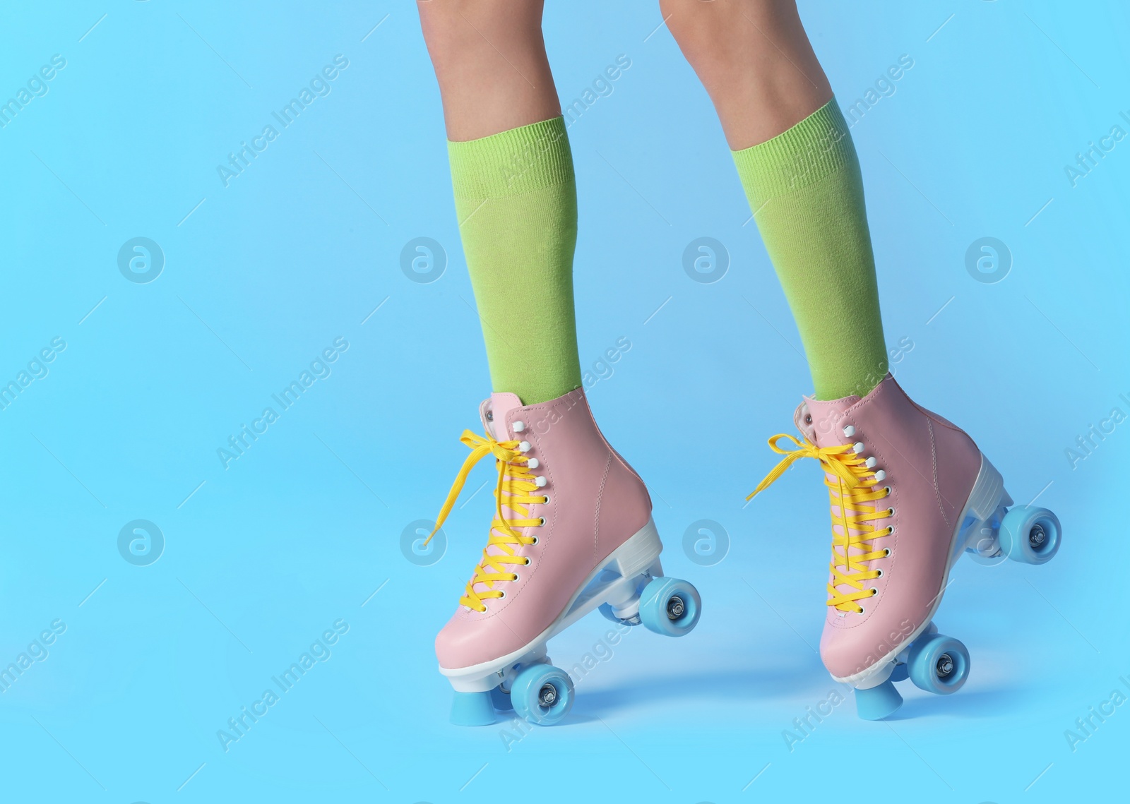 Photo of Woman with vintage roller skates on color background, closeup. Space for text