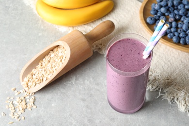 Glass with blueberry smoothie on grey table