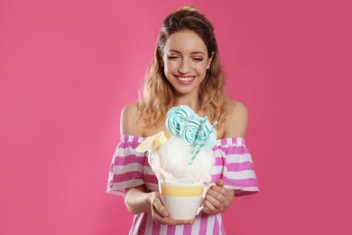 Photo of Portrait of young woman holding cotton candy dessert on color background