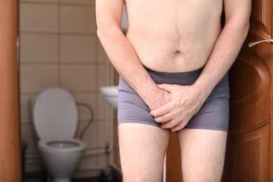 Photo of Mature man with urological problems suffering from pain near toilet