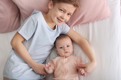 Photo of Cute little baby with elder brother lying on bed at home