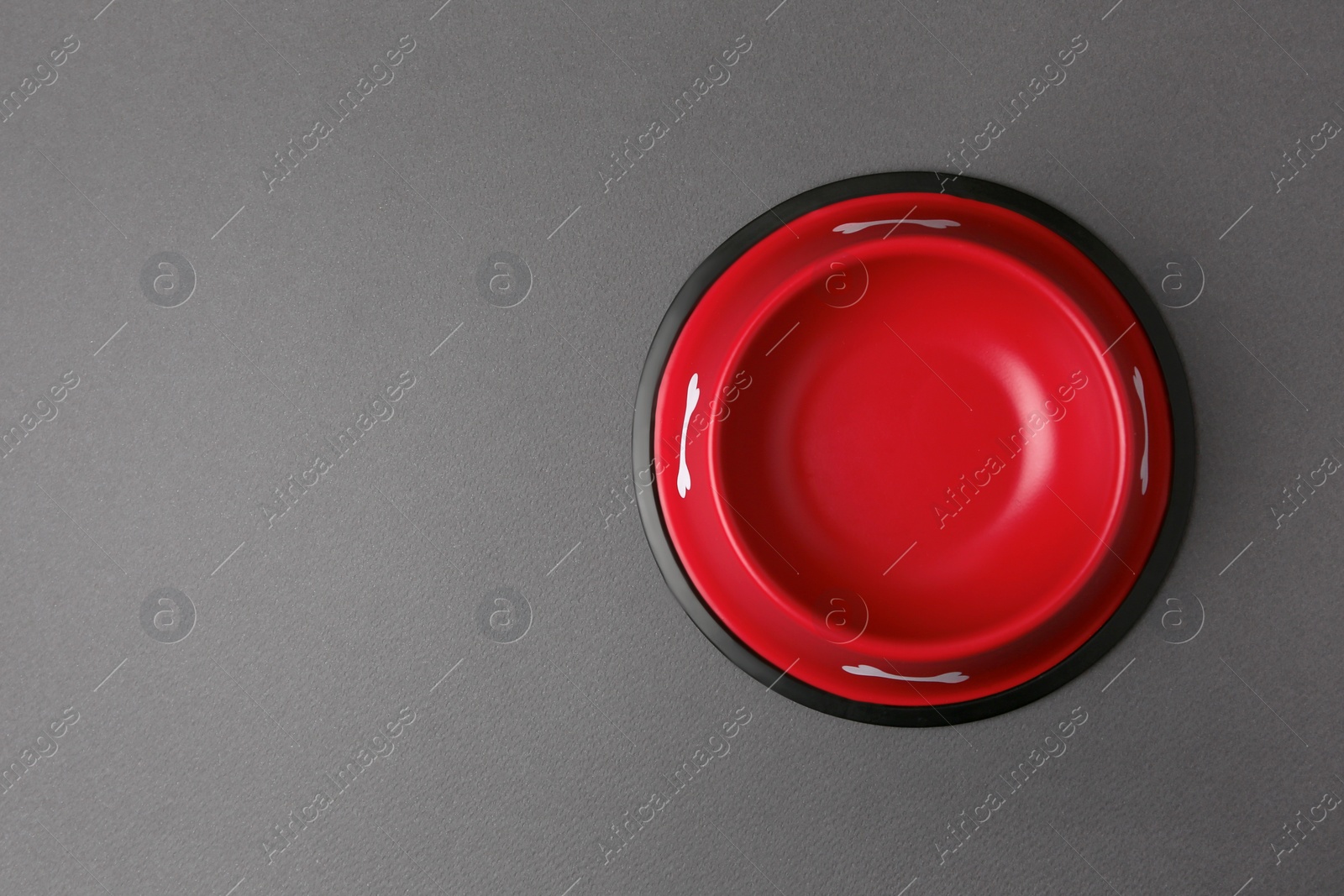 Photo of Empty red feeding bowl on dark grey background, top view. Space for text