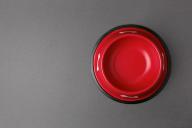 Empty red feeding bowl on dark grey background, top view. Space for text