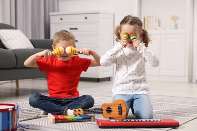 Little children playing toy musical instruments at home
