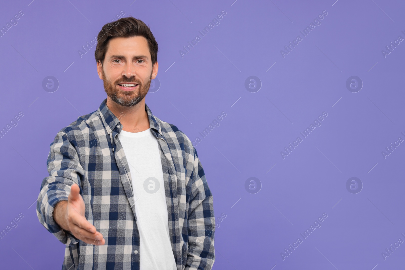 Photo of Happy man welcoming and offering handshake on purple background. Space for text