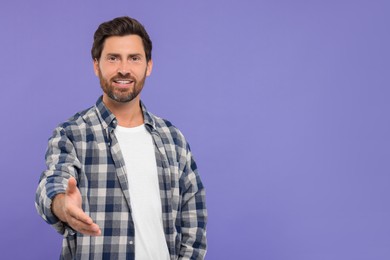 Happy man welcoming and offering handshake on purple background. Space for text