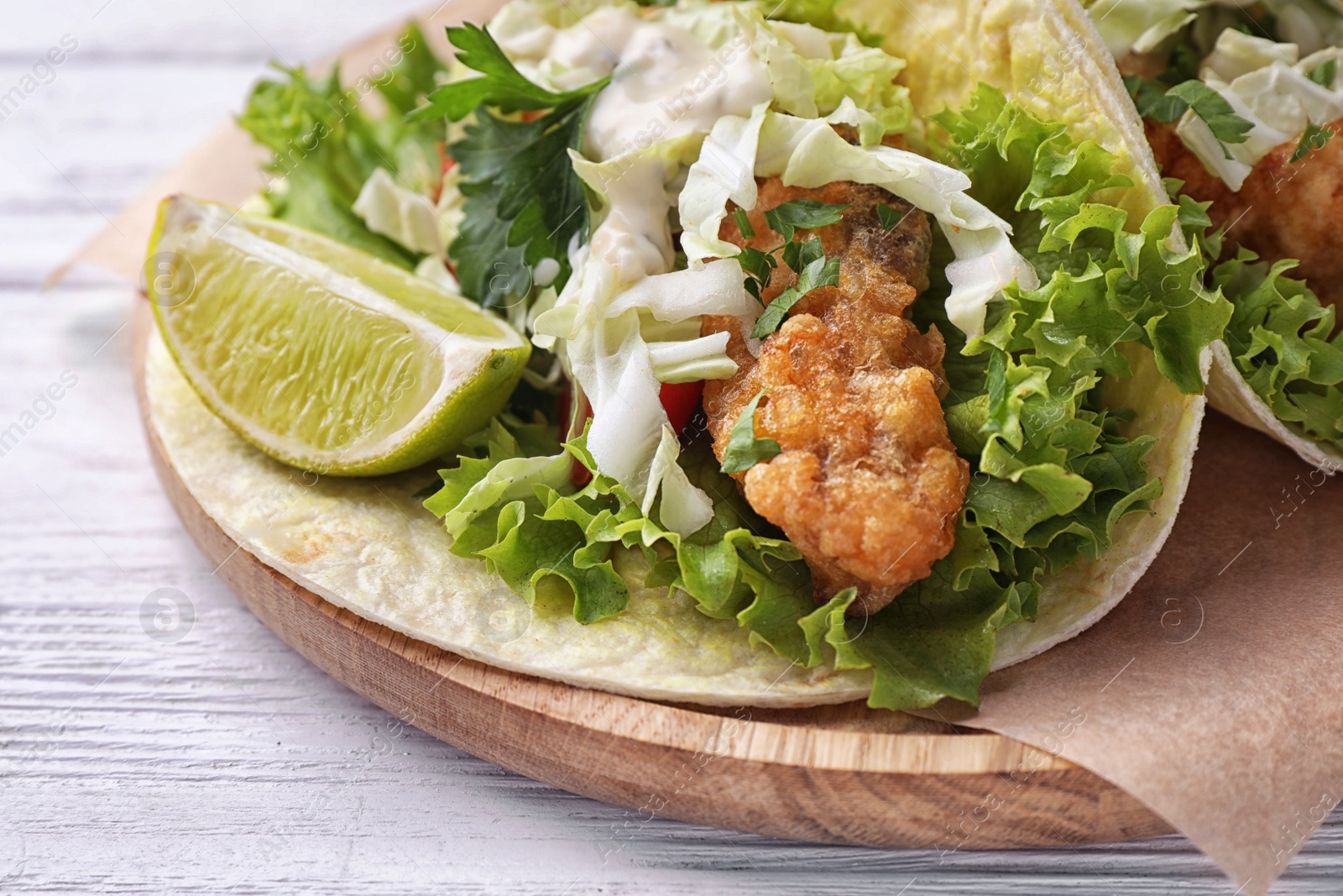 Photo of Yummy fish tacos served on white wooden table, closeup