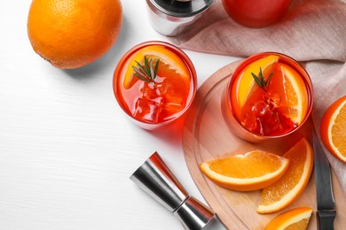 Aperol spritz cocktail, rosemary and orange slices in glasses on white wooden table, flat lay. Space for text