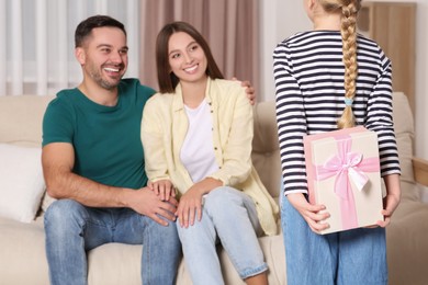 Photo of Little girl presenting her parents with gift at home