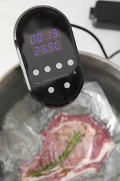 Sous vide cooker and vacuum packed meat in pot on table, closeup. Thermal immersion circulator