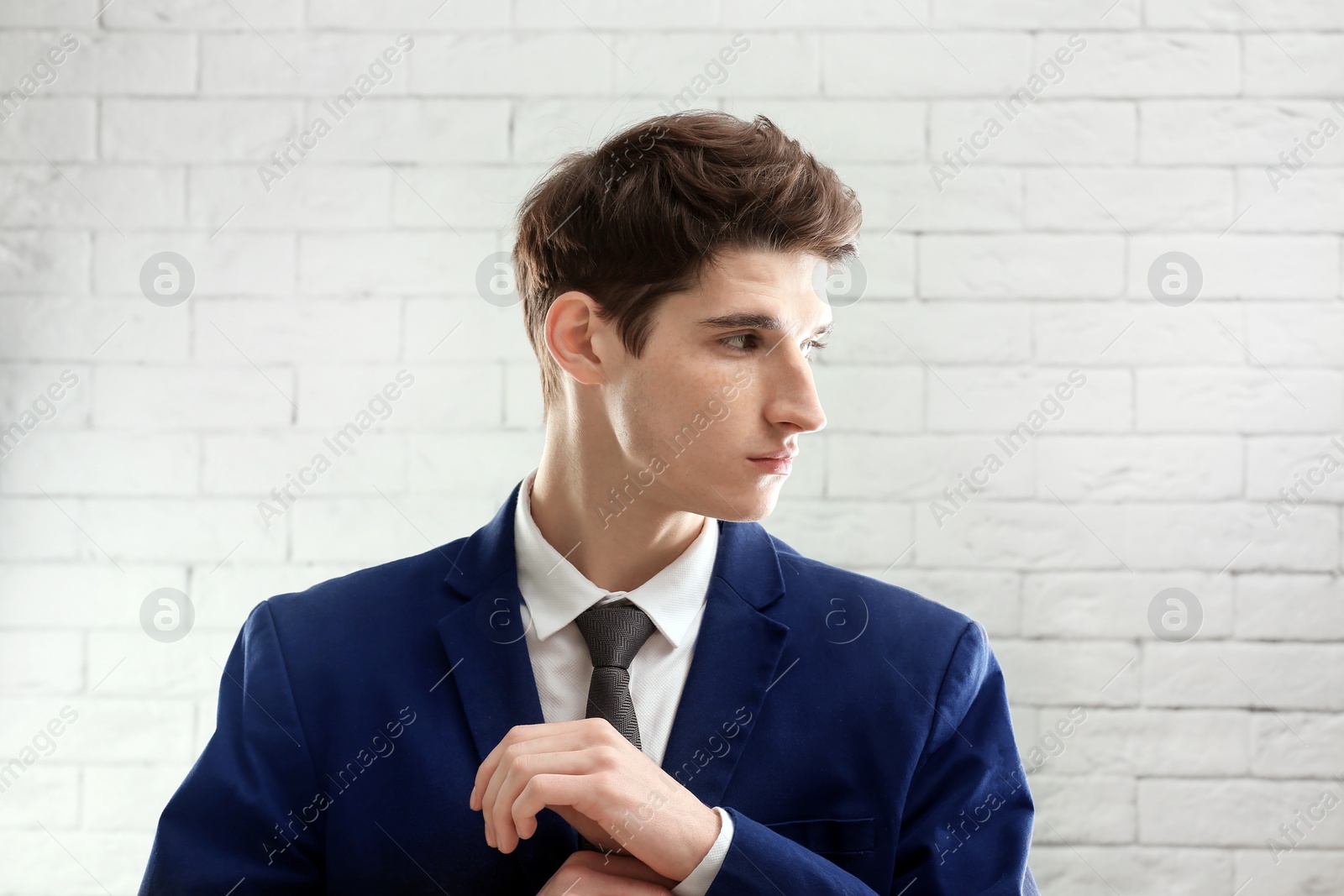 Photo of Portrait of young businessman with beautiful hair on brick wall background